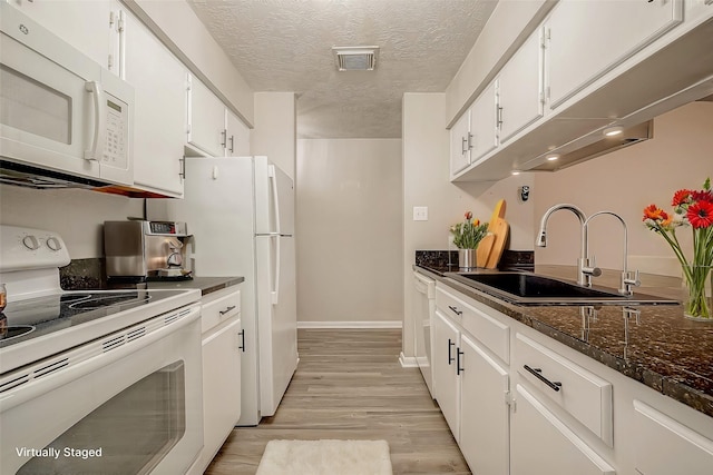 kitchen with sink, dark stone countertops, white cabinets, white appliances, and a textured ceiling