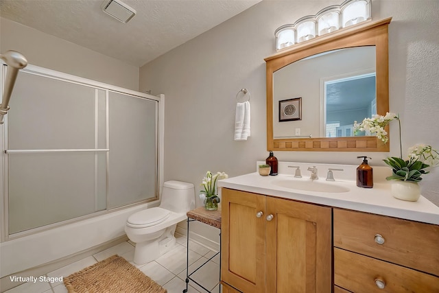 full bathroom featuring combined bath / shower with glass door, tile patterned flooring, vanity, toilet, and a textured ceiling