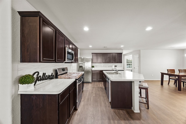 kitchen featuring tasteful backsplash, stainless steel appliances, a kitchen island with sink, and light hardwood / wood-style floors