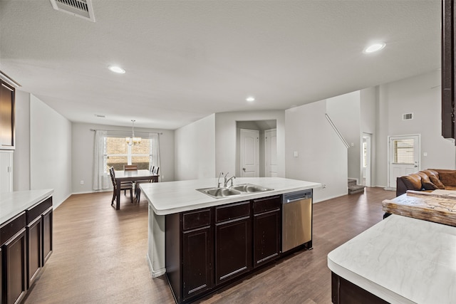 kitchen featuring stainless steel dishwasher, dark wood-type flooring, sink, hanging light fixtures, and an island with sink