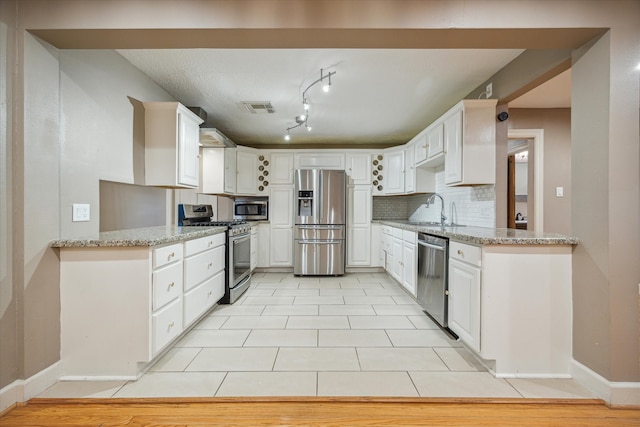 kitchen with tasteful backsplash, white cabinetry, light stone countertops, and appliances with stainless steel finishes