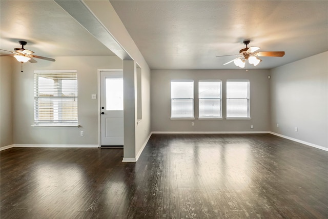 unfurnished living room featuring ceiling fan and dark wood-type flooring