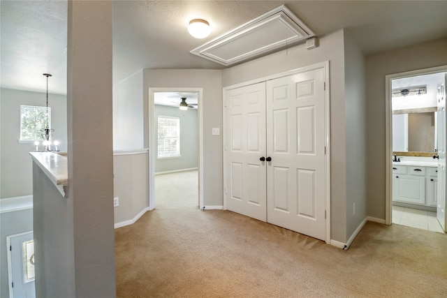 corridor featuring a notable chandelier and light colored carpet