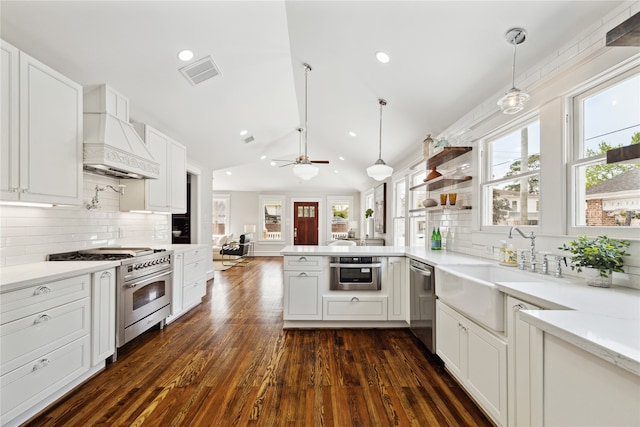 kitchen featuring hanging light fixtures, stainless steel appliances, dark hardwood / wood-style flooring, premium range hood, and kitchen peninsula