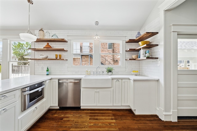 kitchen featuring white cabinets, appliances with stainless steel finishes, decorative light fixtures, and dark hardwood / wood-style floors