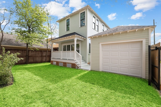 back of house featuring covered porch, a garage, an outdoor structure, and a lawn