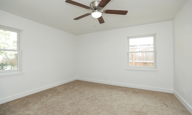 carpeted spare room featuring plenty of natural light and ceiling fan