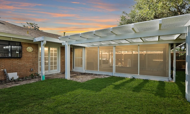 back house at dusk with a yard and a pergola