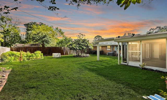 yard at dusk featuring a sunroom and cooling unit