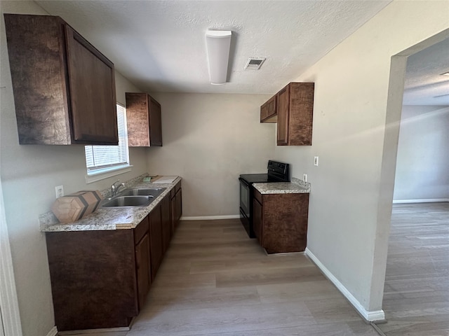 kitchen with dark brown cabinetry, light hardwood / wood-style flooring, black / electric stove, and sink