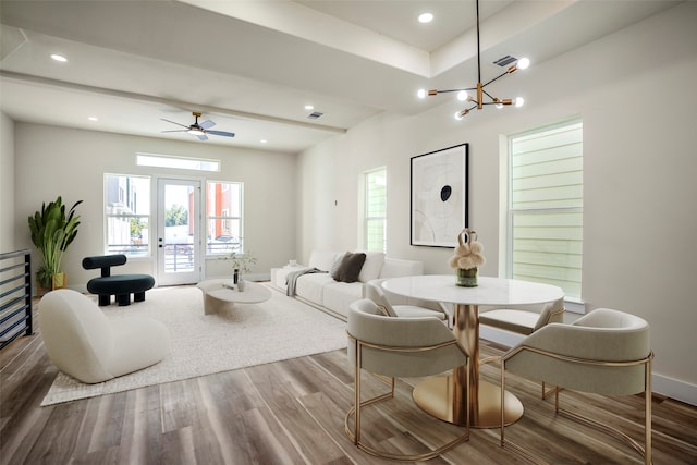 dining area with wood-type flooring, ceiling fan with notable chandelier, and a healthy amount of sunlight