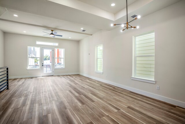 spare room featuring wood-type flooring and ceiling fan with notable chandelier