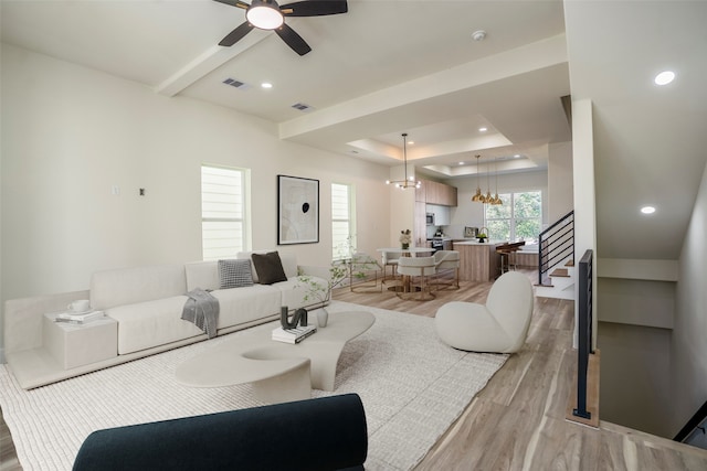 living room with ceiling fan with notable chandelier and light hardwood / wood-style floors