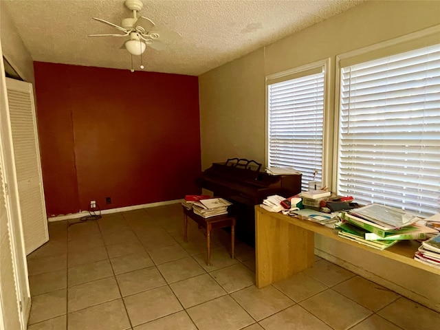 unfurnished office with ceiling fan, light tile patterned flooring, and a textured ceiling