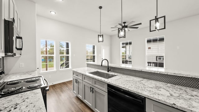 kitchen with light stone countertops, sink, dark hardwood / wood-style floors, pendant lighting, and black appliances