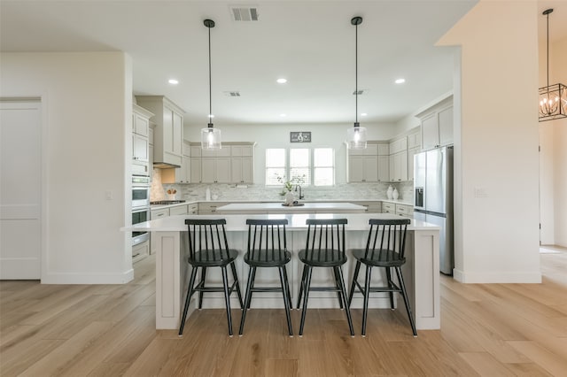 kitchen featuring a large island, hanging light fixtures, stainless steel appliances, and light hardwood / wood-style floors