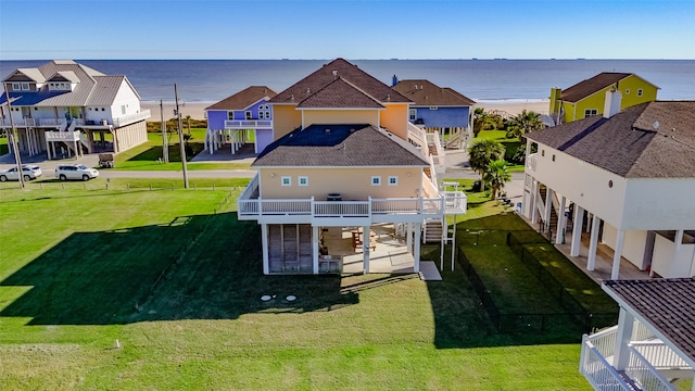 rear view of property featuring a patio area, a lawn, a balcony, and a water view