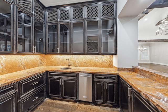 kitchen featuring backsplash, dark wood-type flooring, sink, an inviting chandelier, and hanging light fixtures