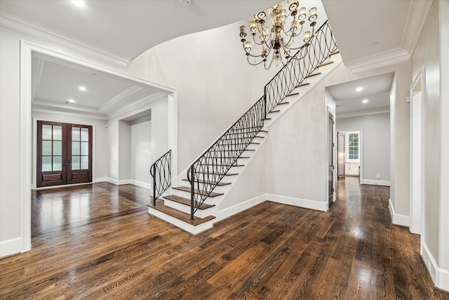 entryway with a notable chandelier, dark hardwood / wood-style floors, crown molding, and french doors