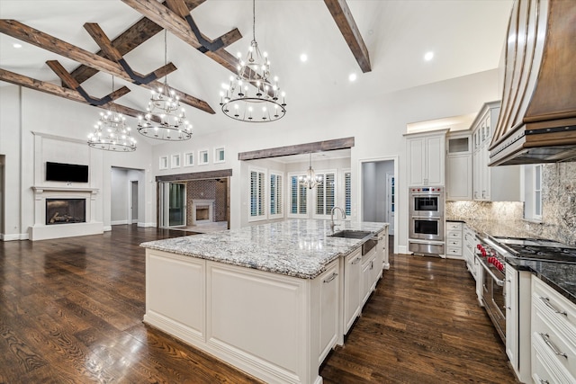 kitchen featuring beamed ceiling, a large island, stainless steel appliances, and high vaulted ceiling