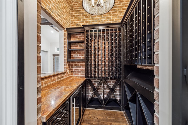 wine cellar with beverage cooler, brick wall, and wood-type flooring