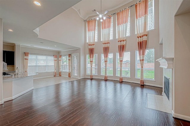 unfurnished living room featuring crown molding, sink, a towering ceiling, and dark hardwood / wood-style floors