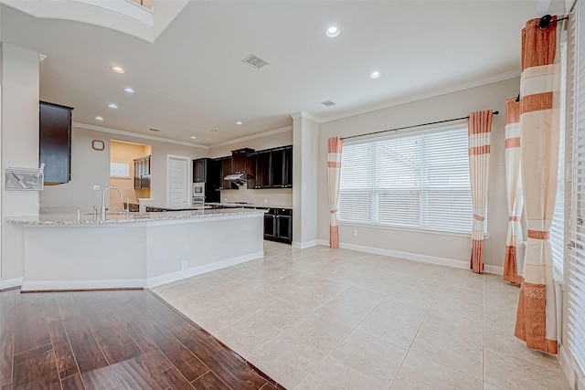 kitchen featuring sink, light hardwood / wood-style flooring, light stone countertops, ornamental molding, and kitchen peninsula