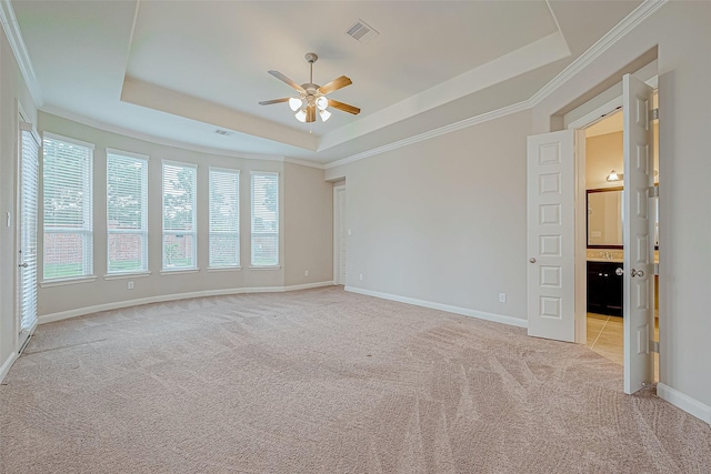 spare room with a raised ceiling, crown molding, ceiling fan, and light carpet