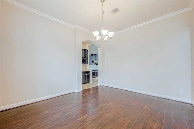 empty room with crown molding, dark wood-type flooring, and a notable chandelier