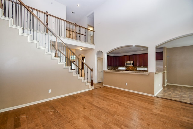 unfurnished living room featuring a towering ceiling and light hardwood / wood-style floors