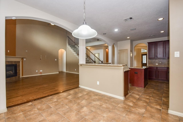 kitchen featuring light stone countertops, tasteful backsplash, wood-type flooring, decorative light fixtures, and a fireplace