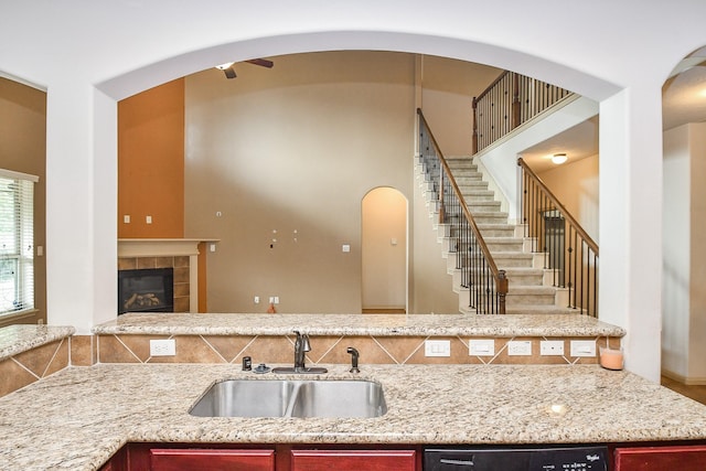 kitchen with dishwasher, a tiled fireplace, and sink