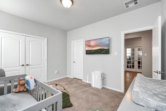 carpeted bedroom featuring a closet and a nursery area