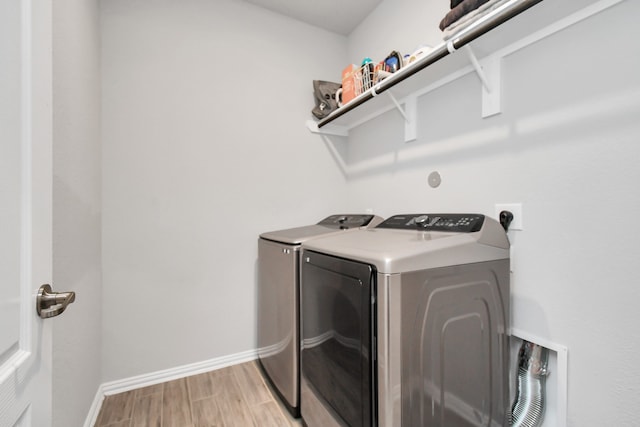 clothes washing area with washer and dryer and light wood-type flooring