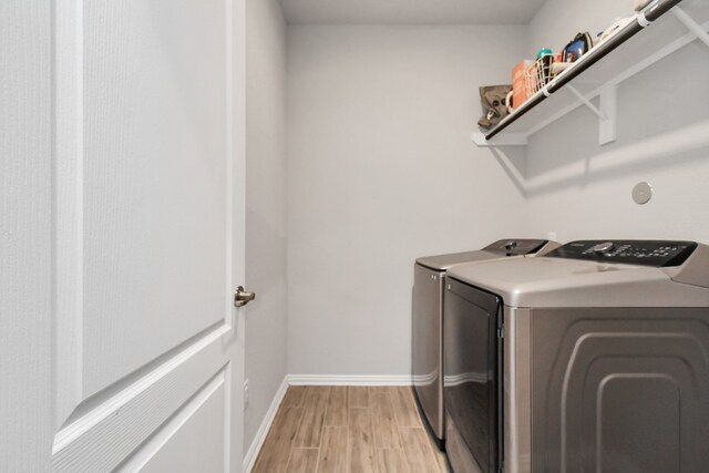 laundry area with washer and clothes dryer and light hardwood / wood-style flooring