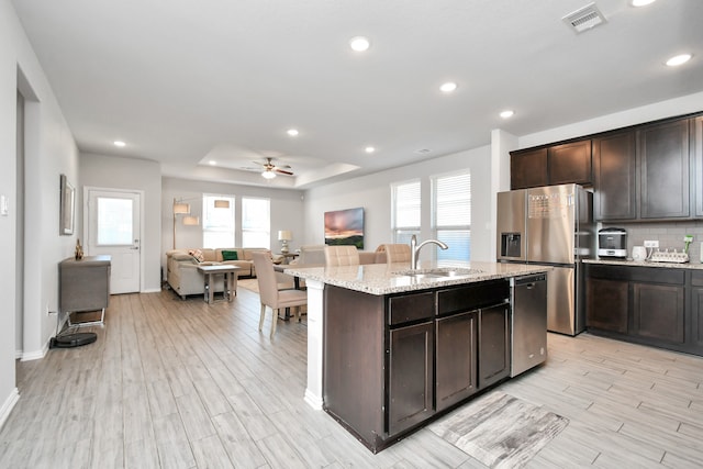 kitchen featuring appliances with stainless steel finishes, sink, a wealth of natural light, and an island with sink