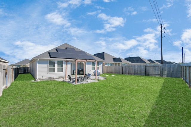 rear view of house featuring a patio area, a yard, and solar panels