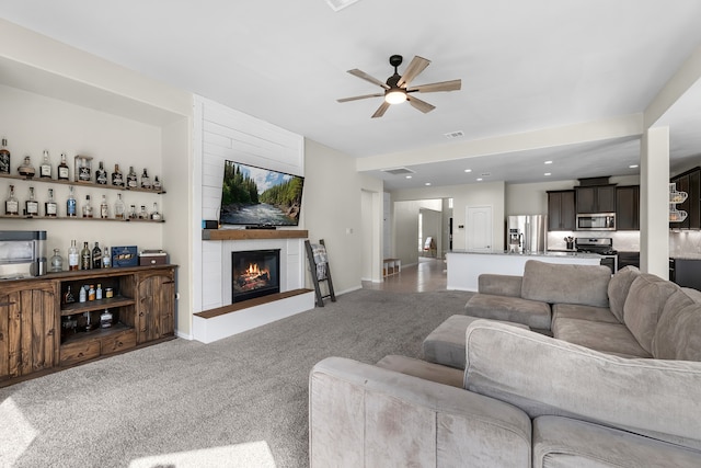 carpeted living room with a fireplace and ceiling fan