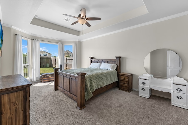 bedroom featuring a tray ceiling, ceiling fan, crown molding, and light carpet