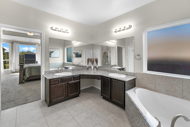 bathroom with tile patterned flooring, vanity, and a relaxing tiled tub