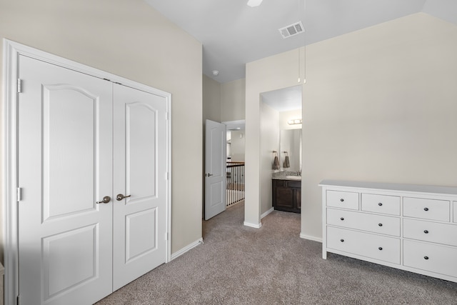 unfurnished bedroom featuring vaulted ceiling, ceiling fan, connected bathroom, light colored carpet, and a closet