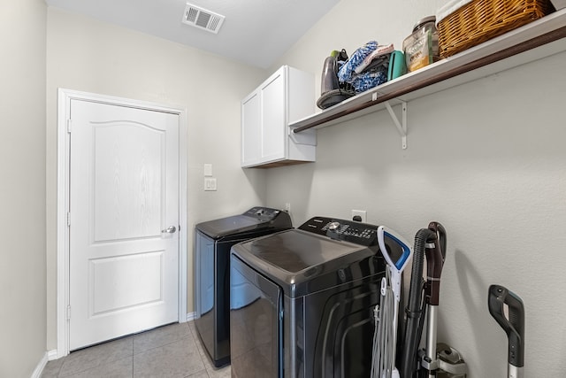 laundry room with cabinets, washing machine and dryer, and light tile patterned flooring