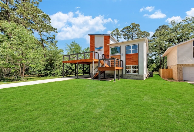 rear view of property featuring a garage, a yard, and a wooden deck