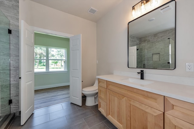 bathroom with hardwood / wood-style floors, vanity, toilet, and walk in shower