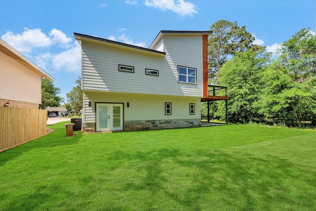 rear view of property with a lawn, central AC, and french doors