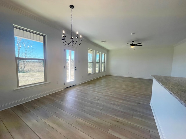 unfurnished dining area featuring ceiling fan with notable chandelier, light wood finished floors, visible vents, and baseboards