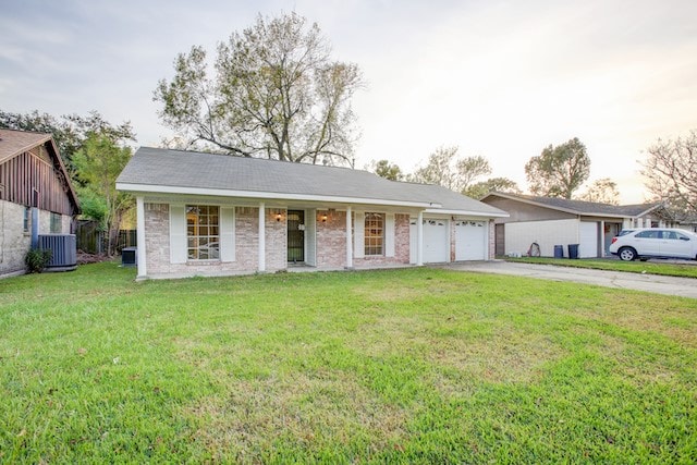 ranch-style home featuring cooling unit, covered porch, a front yard, and a garage