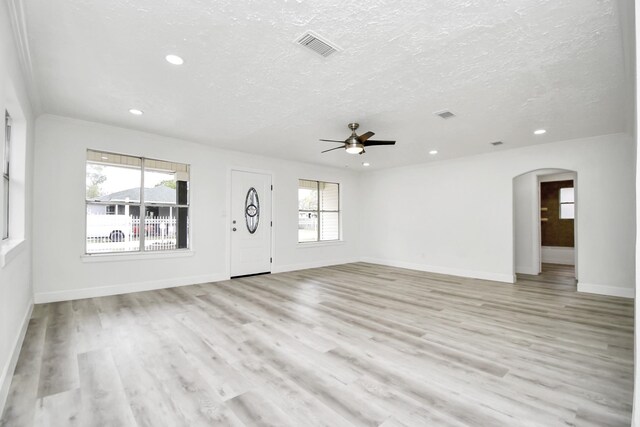 unfurnished living room with a wealth of natural light, ceiling fan, a textured ceiling, and light wood-type flooring