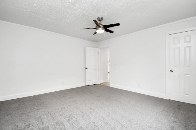 spare room with ceiling fan, ornamental molding, a textured ceiling, and dark colored carpet