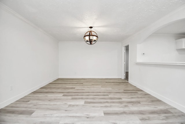 interior space with a textured ceiling, an inviting chandelier, light hardwood / wood-style flooring, and crown molding